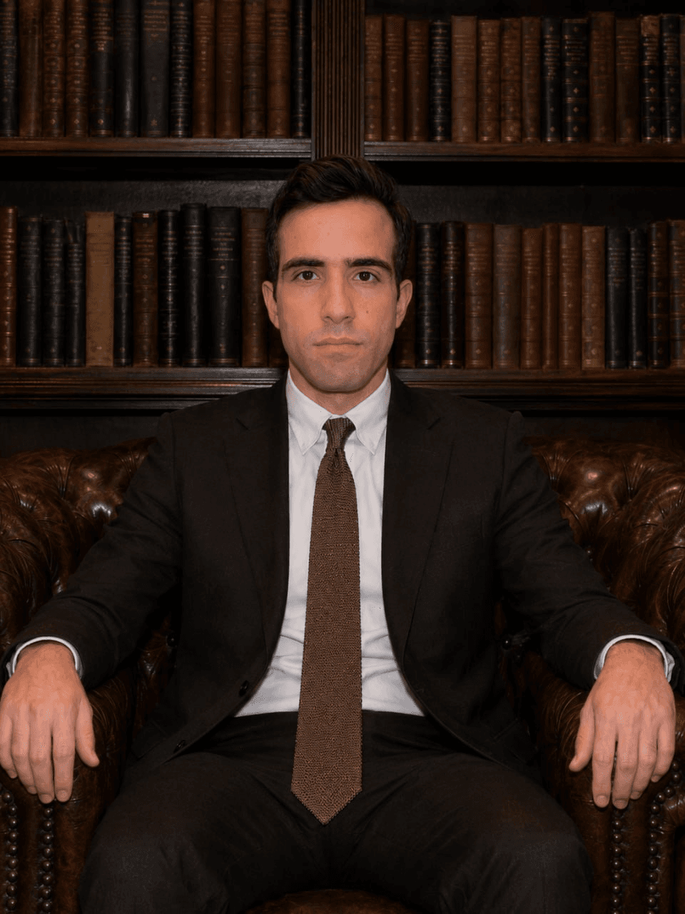 Adam J. De Collibus seated in a library